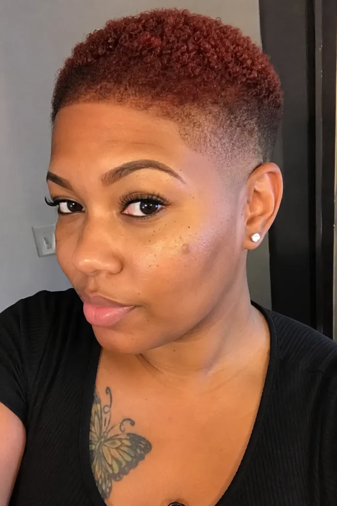 a Black woman around 25–35 years old with an auburn bald fade hairstyle, featuring rich warm hair color,