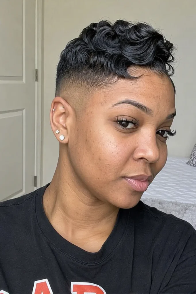 a Black woman in her late 20s to early 30s with soft waves styled on top and a clean bald fade haircut.