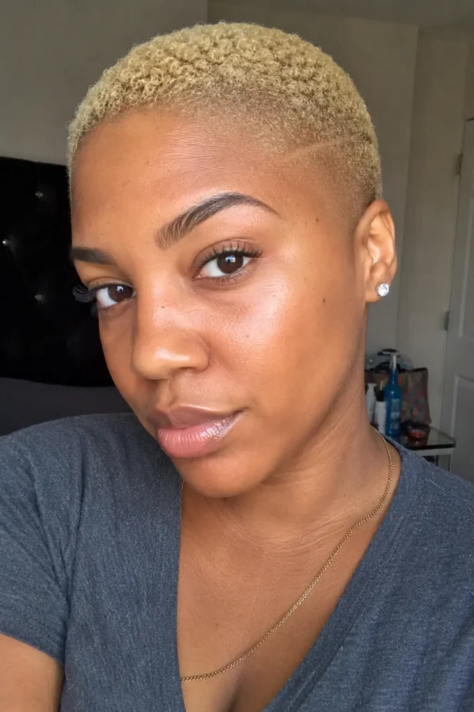 a real Black woman in her late 20s to early 30s with a blonde bald fade hairstyle, featuring realistic skin texture