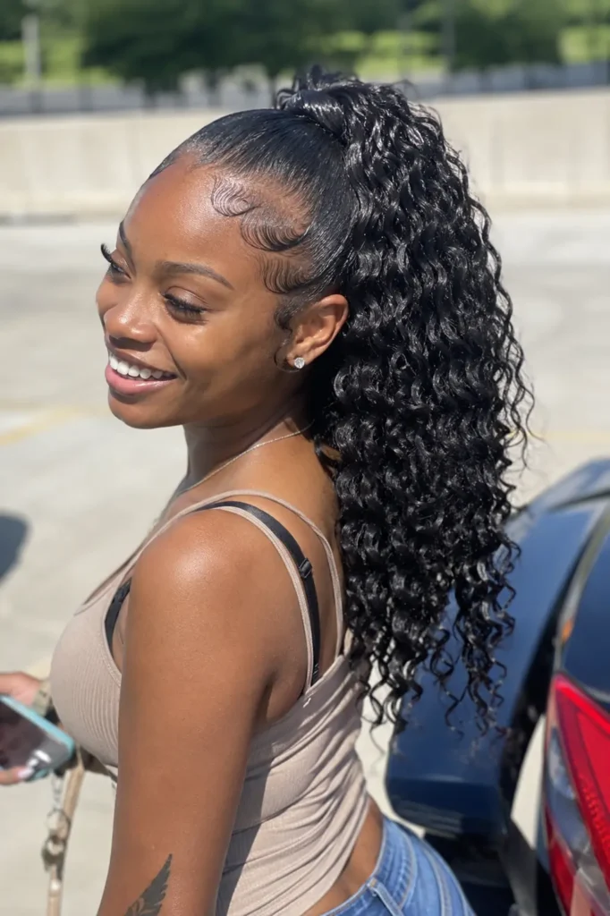young woman with natural skin texture and styled baby hairs wearing a curly quick weave ponytail with defined cascading curls