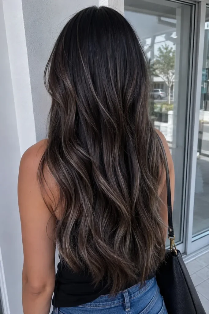 ack-view portrait of a real woman with long dark espresso hair featuring dusty silver ash babylights, styled in soft natural waves