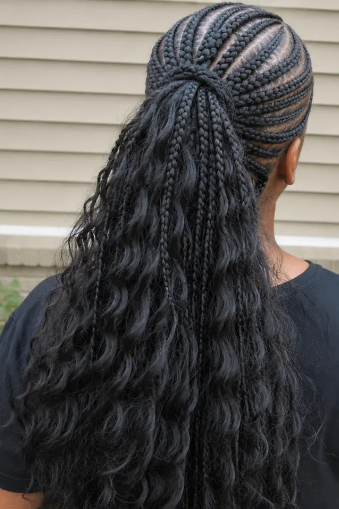 Back view of a real Black woman wearing a cornrow half up half down ponytail hairstyle, featuring neat scalp braids flowing into a high ponytail with long wavy hair cascading down her back