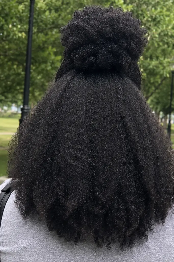 back side of girl  has Half Up Half Down Sew-In Waves wearing gray shirt