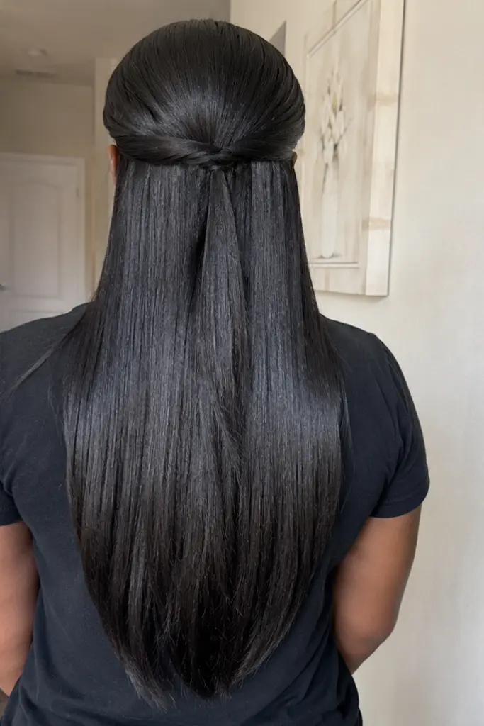 Back view of a real Black woman wearing a sleek silk press half up half down hairstyle, featuring glossy straight hair flowing smoothly down her back with a polished top section