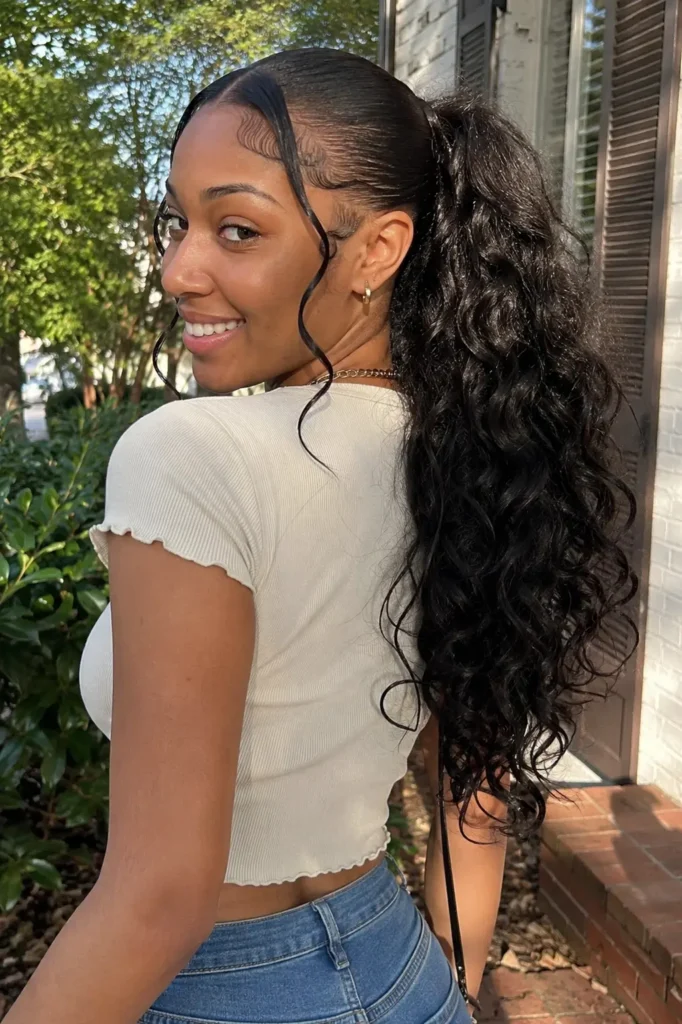 Romantic loose curly quick weave ponytail hairstyle on a real woman aged 22–28 with natural facial features and realistic skin texture, smiling candidly in daylight