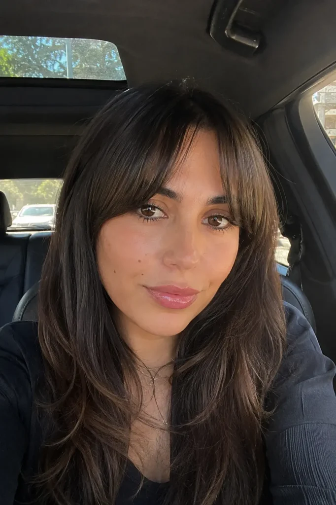 a young woman with slick front hair worn down and soft curtain bangs framing her face
