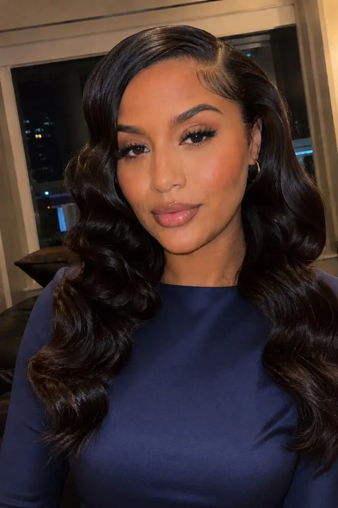 a glamorous young woman with sleek slicked-front hair and glossy Hollywood waves cascading over her shoulders.