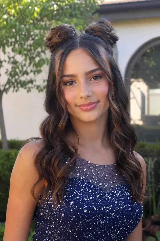 Real teenage girl around 13–14 years old wearing a sparkly navy blue formal dress, styled with glamorous space buns and long loose waves. She has natural facial features, realistic skin texture, soft glam makeup, and a gentle smile.
