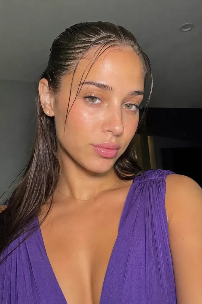 a young woman in a purple dress with wet-look slicked front hair, glossy sleek styling, natural makeup