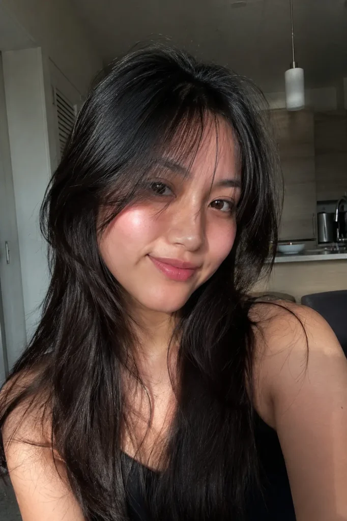 girl with a heart-shaped face and long layered dark hair featuring soft wispy bangs