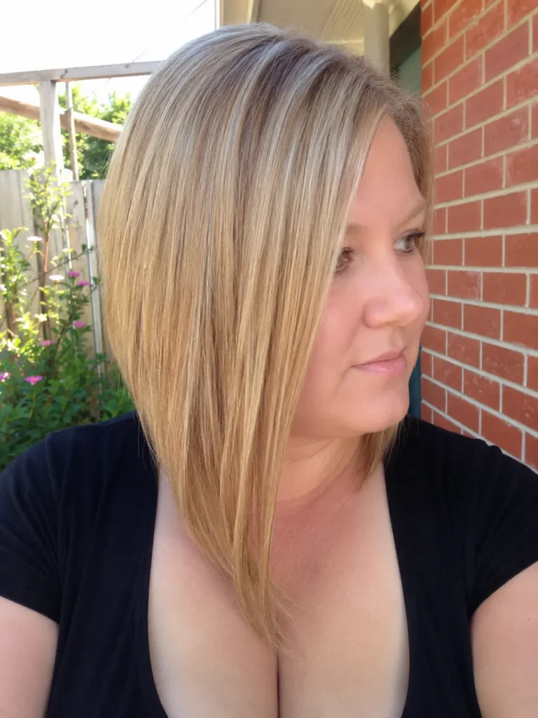 an English plus-size woman with a sleek angled long bob haircut in natural beige blonde, showcasing a precise, longer-front silhouette and glossy healthy hair