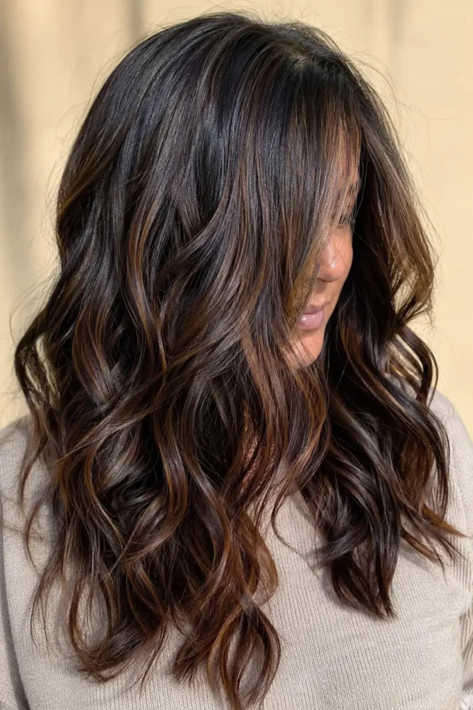 a woman aged 30–50 with long, luxurious black hair featuring seamlessly blended chocolate, mocha, chestnut, and caramel brown highlights
