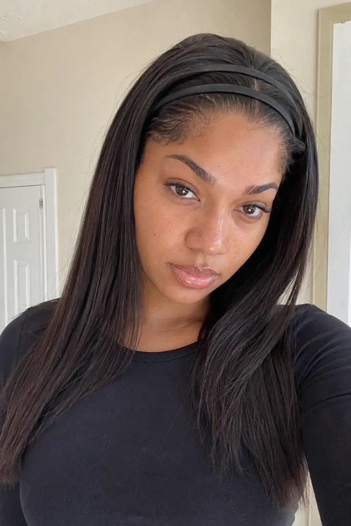 Realistic portrait of a 22-year-old woman with a double black headband hairstyle and sleek, straight dark hair. She has natural facial features, subtle makeup, and visible skin texture, posing indoors with soft lighting