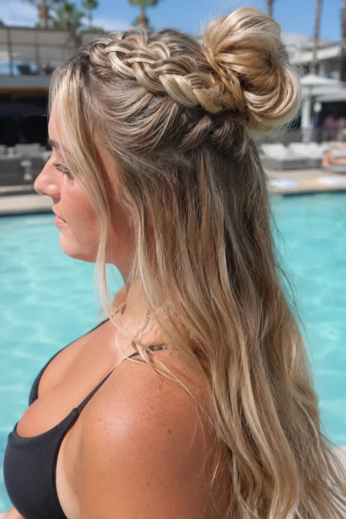 woman with a detailed half-up braided bun hairstyle and long light golden blonde hair, photographed poolside in bright summer sunshine.