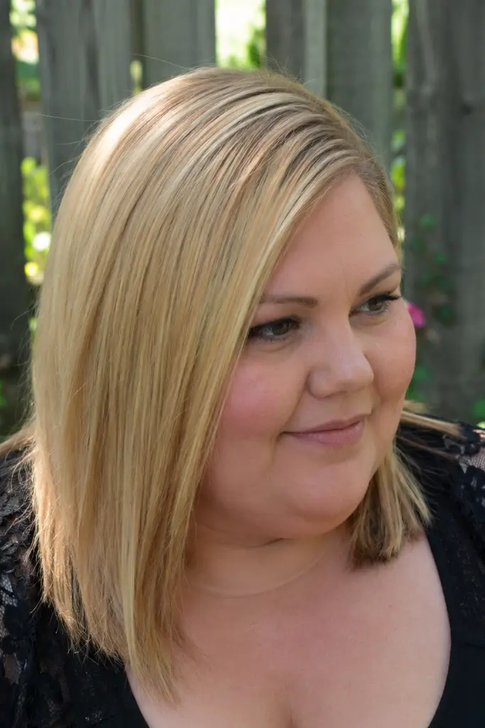 English plus-size woman with sleek, straight medium-length golden blonde hair styled with a deep side part