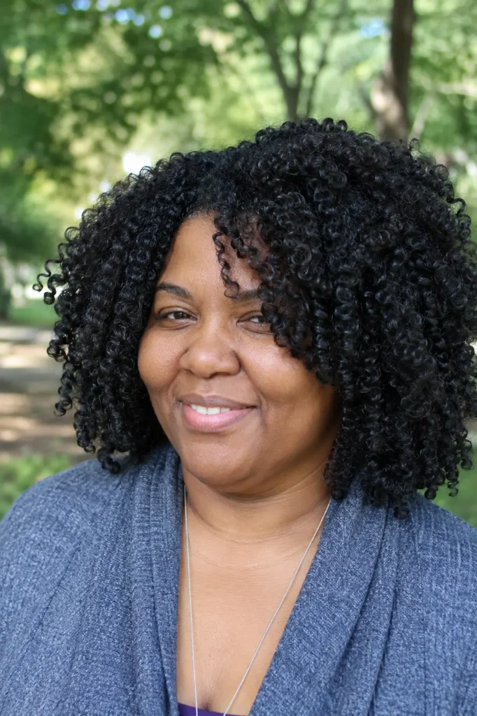 Close-up portrait of a plus-size woman aged 30–55 with wash-and-go natural curls, showcasing healthy, defined ringlets with natural volume and texture. Her curls fill most of the frame, highlighting the authentic curl pattern and minimal styling