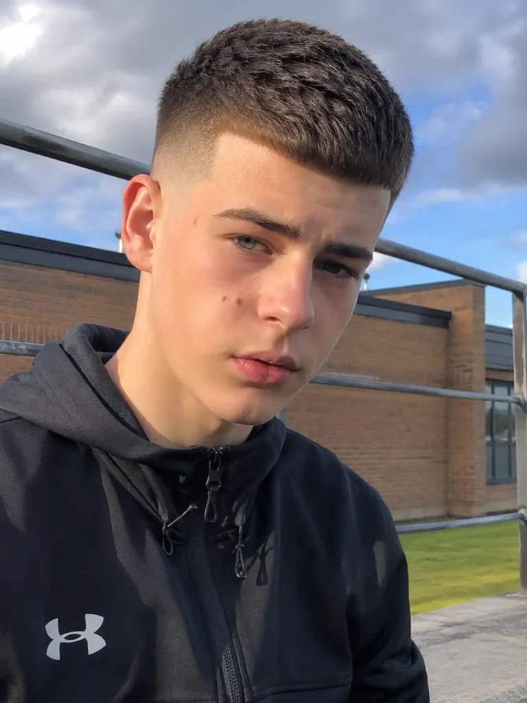 **Alt Text:**
Teenage boy with a skin fade haircut and short textured top, wearing casual sportswear outdoors in natural daylight, showcasing a sharp fade and realistic hairstyle.