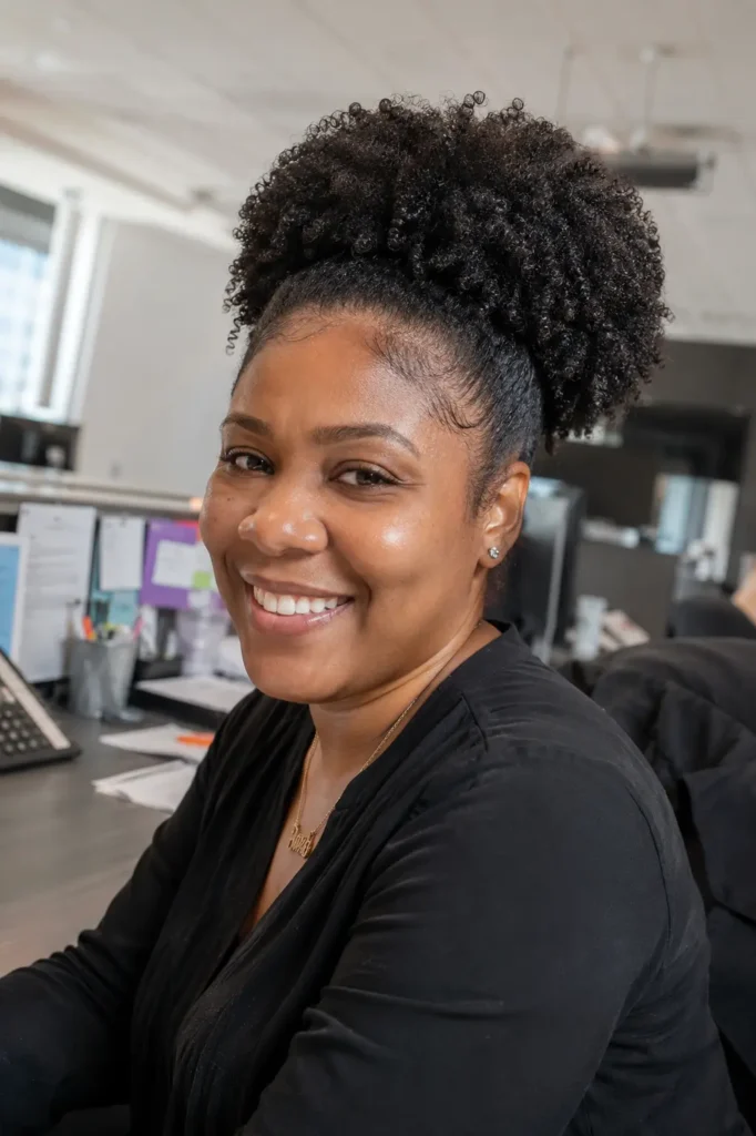 everyday Black woman wearing a wash-and-puff natural hairstyle with freshly defined Type 4 curls gathered into a high puff.