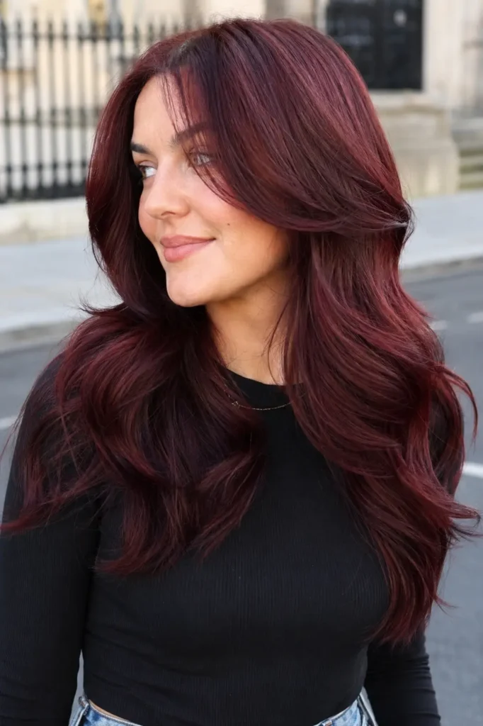 an English woman with cherry cola hair tint, featuring deep red-brown burgundy tones, soft layered waves,