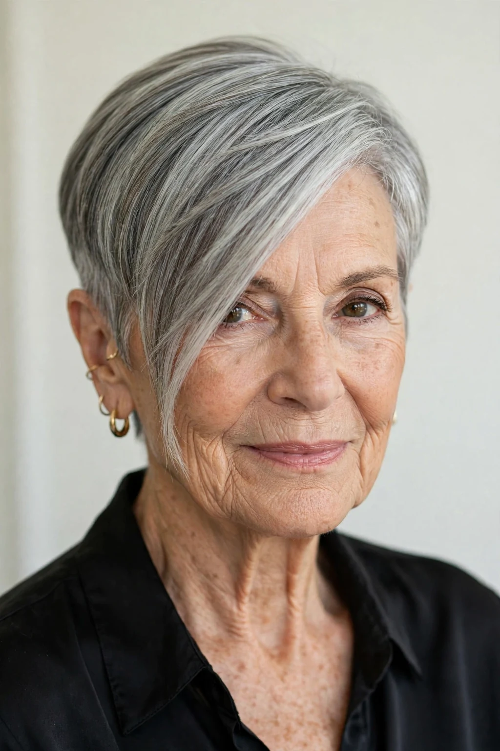 Elegant woman over 70 with asymmetric short cut, modern angled shape, confident light.