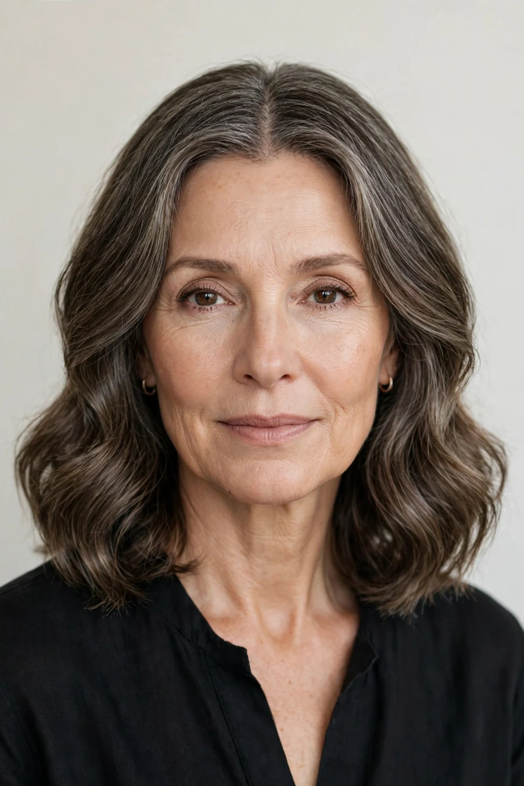 Elegant woman over 50 with center-part soft waves, balanced serene style, calm light.