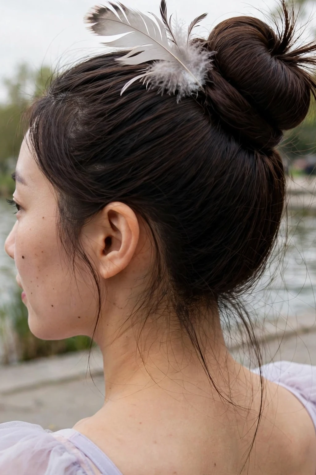 Young Korean woman with an enchanted swan lake bun in a high smooth bun with a feathered accessory, wearing a pale lavender dress by a lakeside promenade.