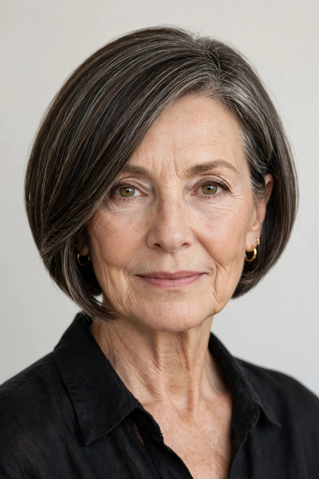 Elegant woman over 60 with inverted bob, angled modern shape, sophisticated light.