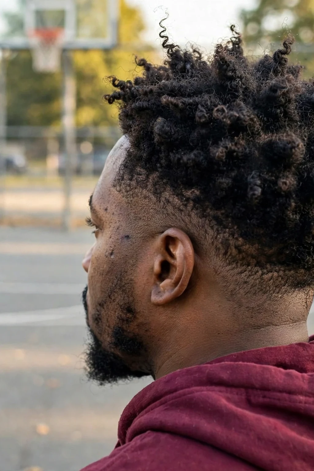 Man with a medium-length coily tapered haircut, defined tight coils on top with clean tapered sides.