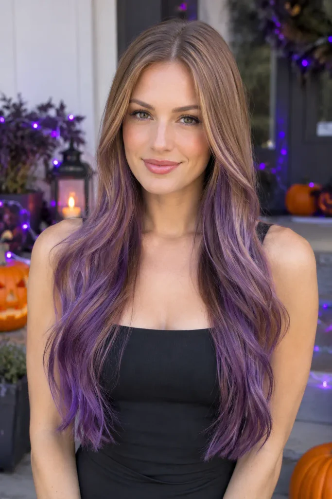 Real young woman with long dark blonde hair tinted violet-purple through the lengths and ends, wearing a black sleeveless dress in front of purple Halloween lights and pumpkins.